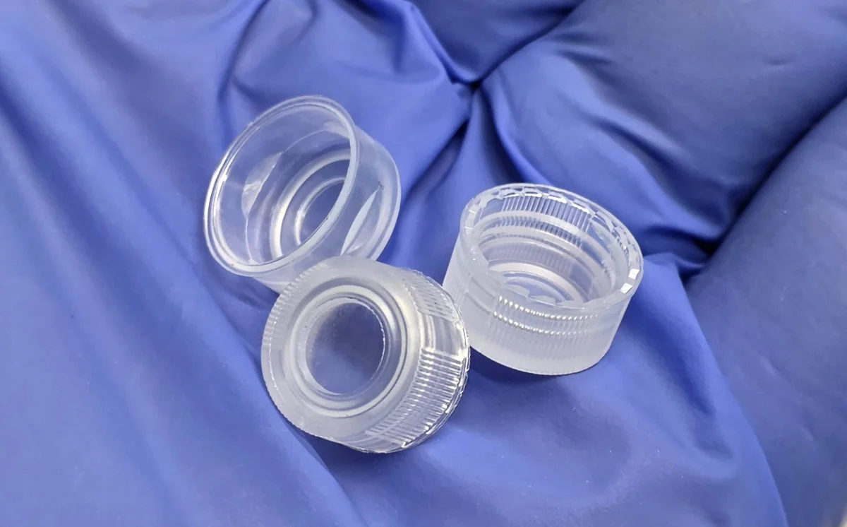 Unlined closures of various sizes held in a gloved hand, designed for single-injection PFAS testing
